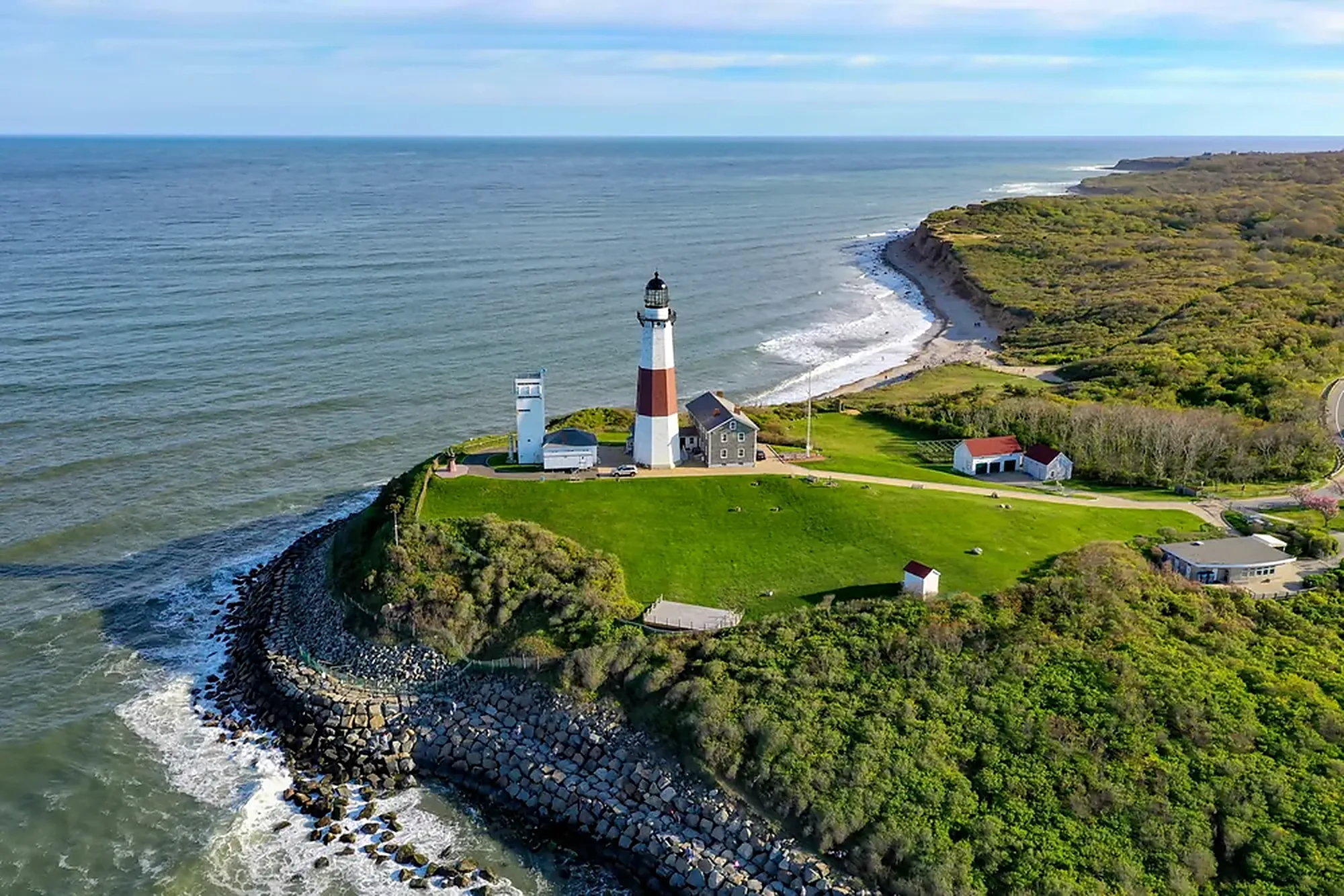 Montauk lighthouse on a green New York bluff above breaking Atlantic surf